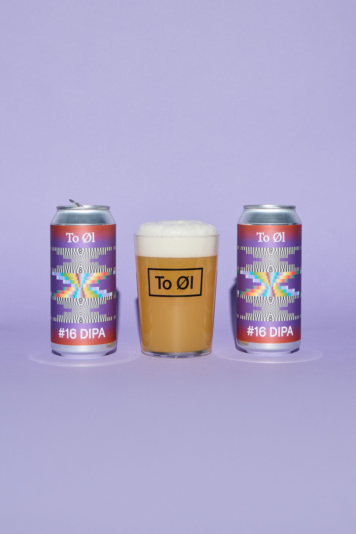 Two To Øl branded cans and a glass of beer arranged on a lavender background. The two cans have colorful geometric labels reading #16 DIPA, and the center glass shows an amber beer with white foam and a black To Øl logo.