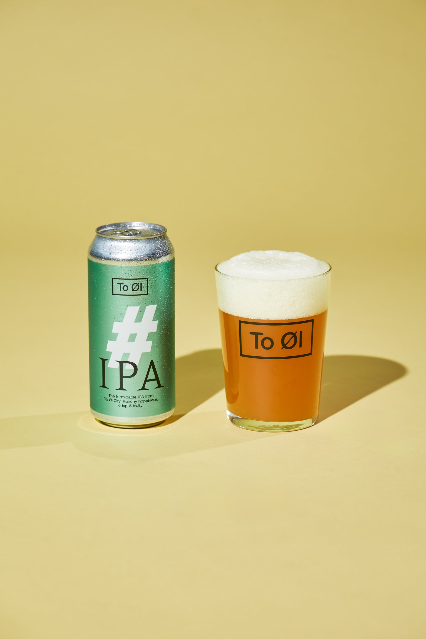 Can and glass of To Øl #IPA on a yellow background