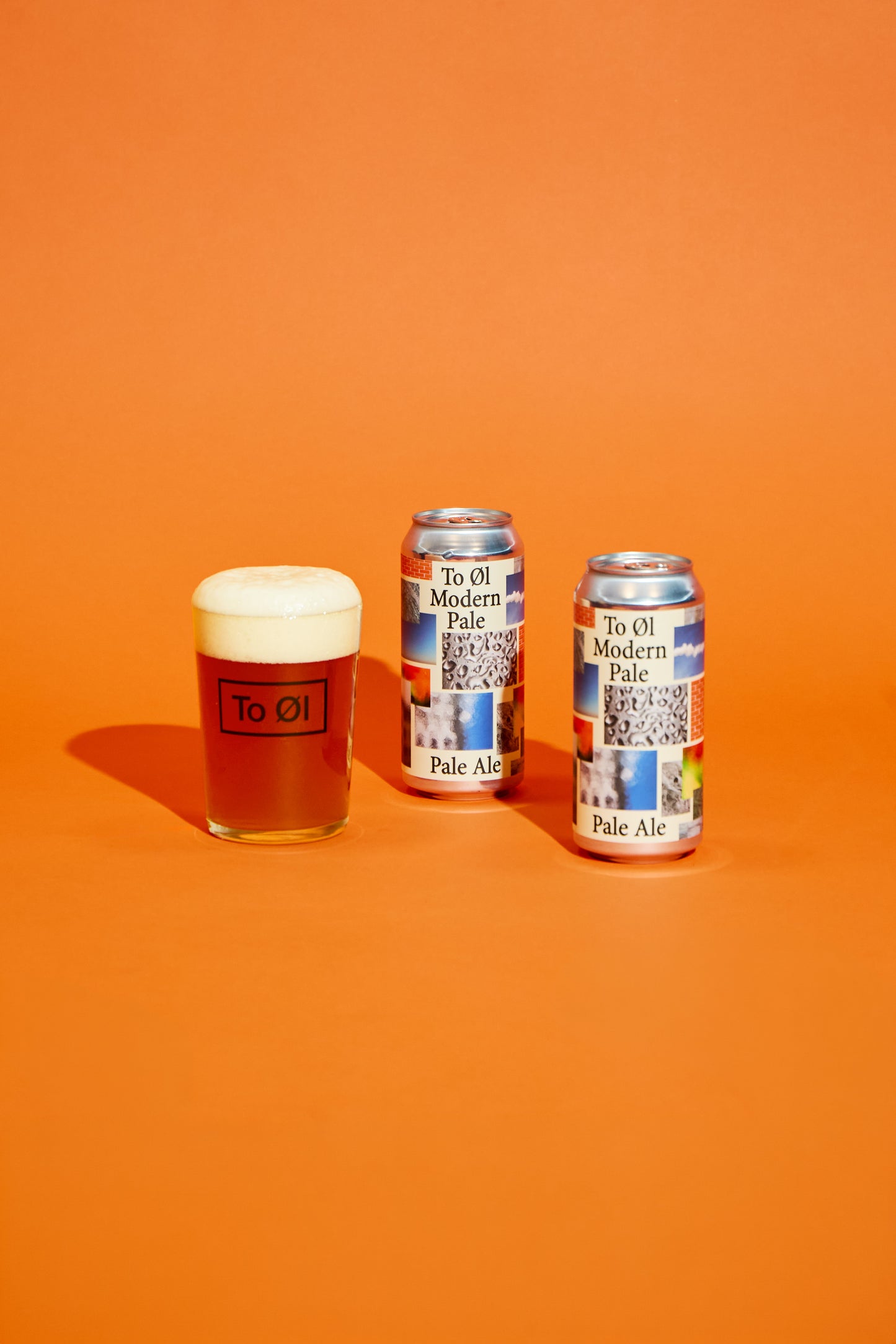 Two cans of To Øl Modern Pale Ale and a glass of beer on an orange background
