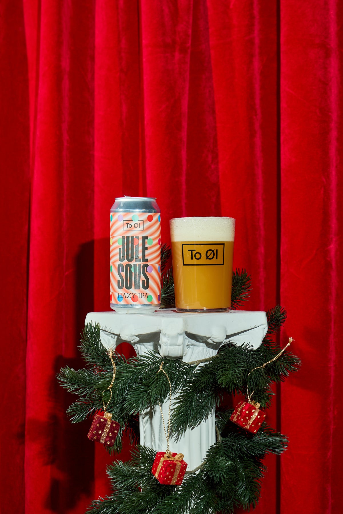 To Øl Julesovs Can and Beer Glass Pour with Christmas Red background.
