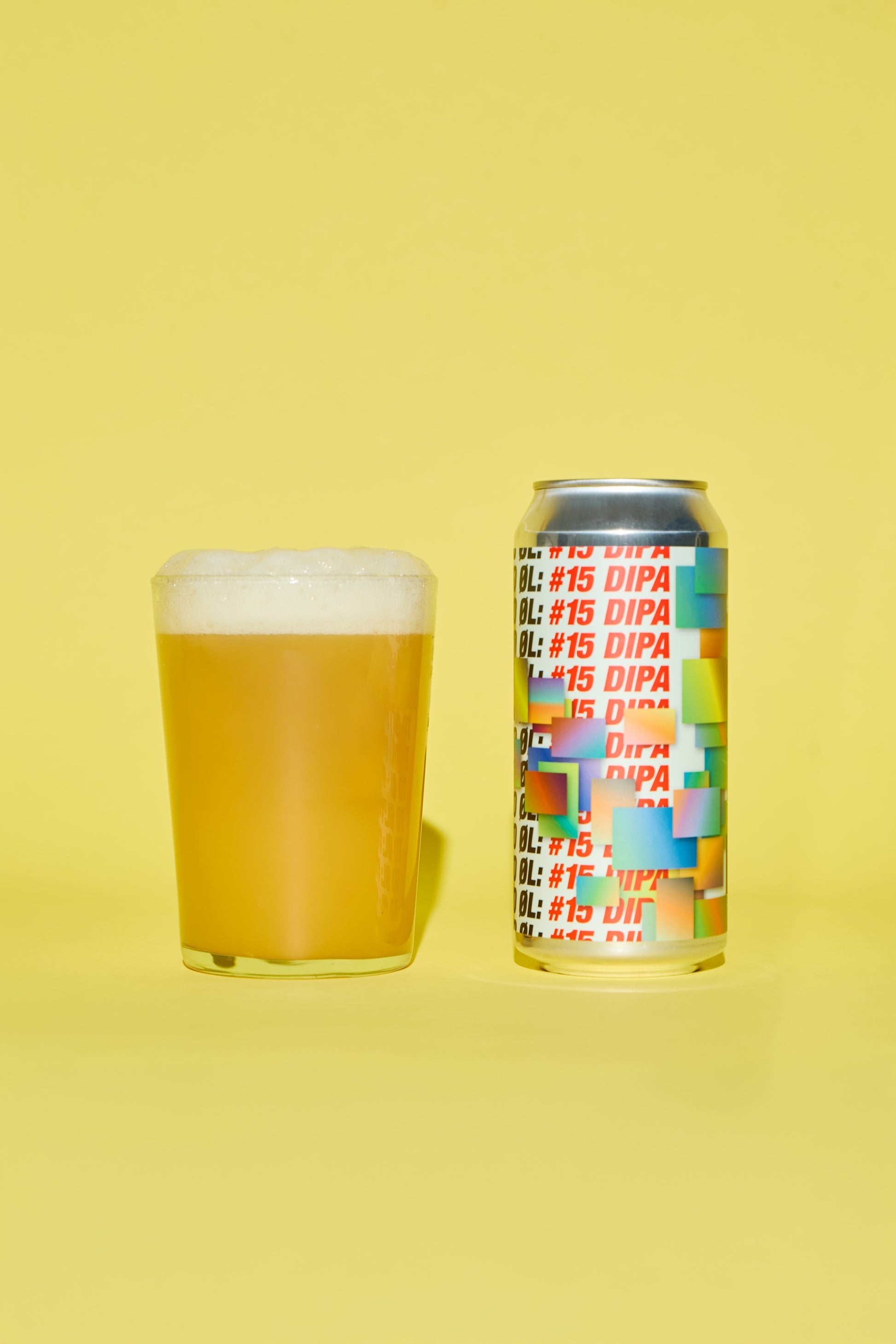 #15 DIPA Beer can with geometrical forms with colorful label and glass of beer on a yellow background.
