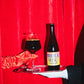 Birramisu bottle by To Øl poured in a pint glass with dark beer and red background.