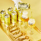 A hand in a white glove pours a golden beverage from a metallic gold can onto two glasses with To Øl Italian Pilsner labels, arranged on a gold tray with matching gold cans and decorative gold bottle opener keychains.