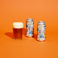 Two cans of To Øl Modern Pale Ale and a glass of beer on an orange background