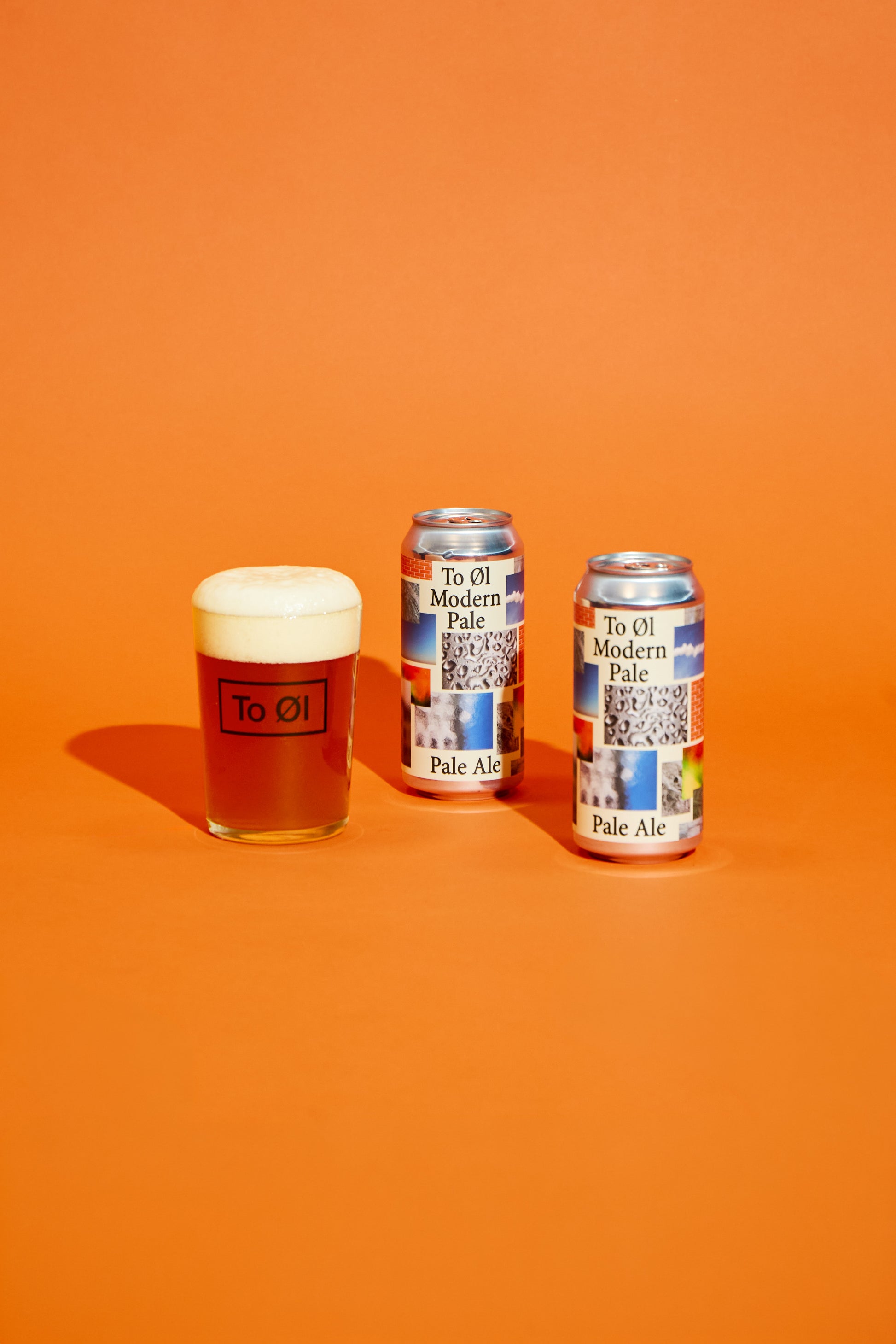 Two cans of To Øl Modern Pale Ale and a glass of beer on an orange background