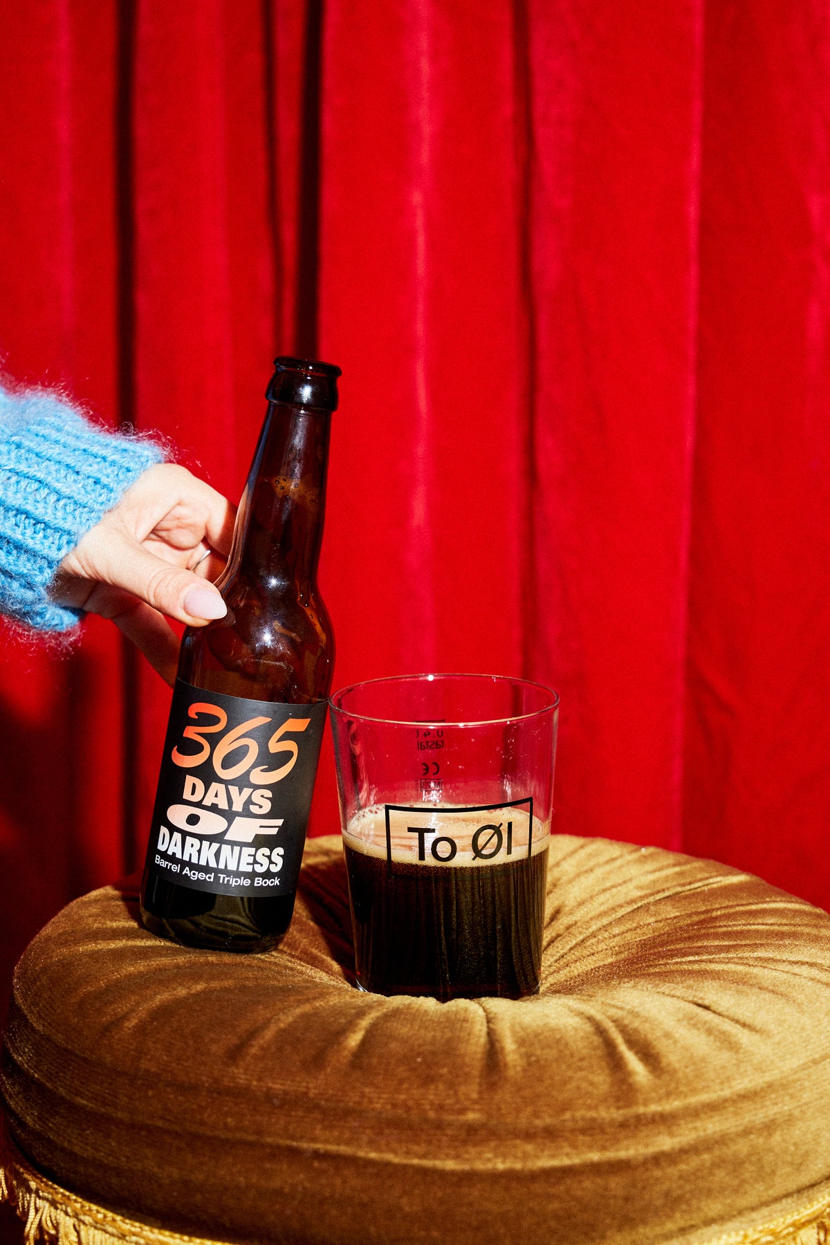 To Øl 365 Days of Darkness poured in a beer glass with red studio background.