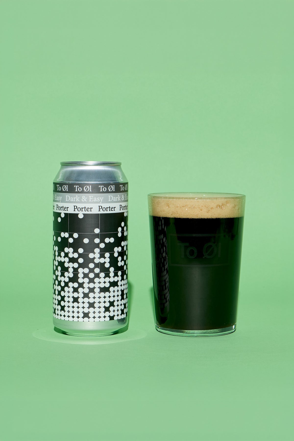 A silver can of To:Ol' Porter Porter alongside a clear glass filled with dark stout beer and a thick tan head, set against a solid light green background.